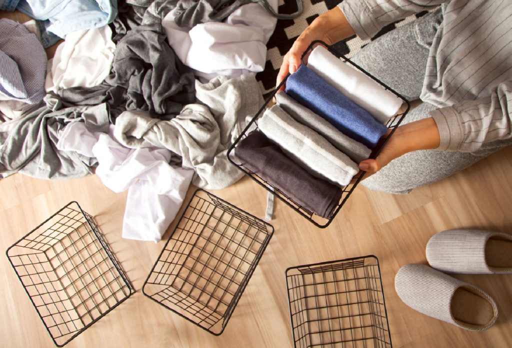woman putting clothes into baskets to organize a closet
