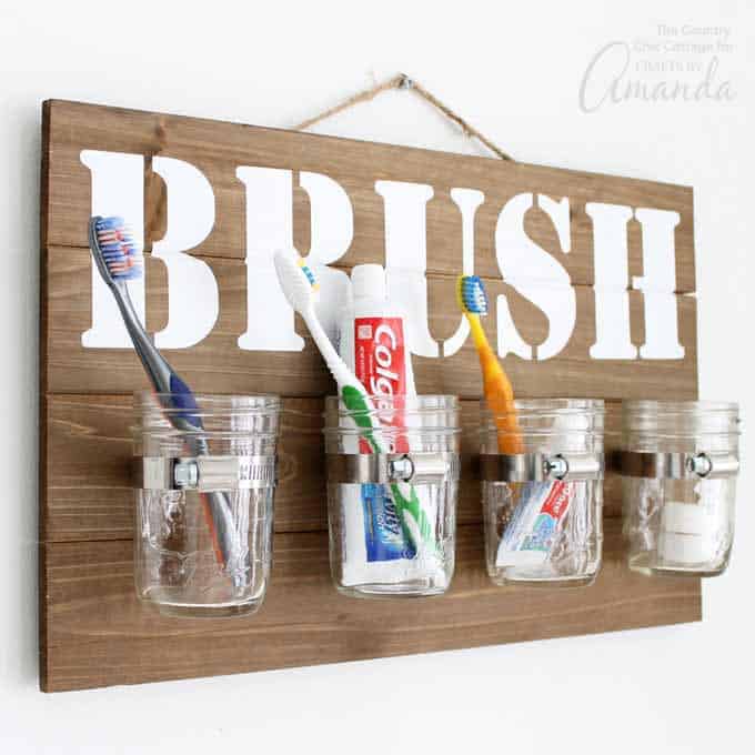 Image that shows a DIY wood Brush sign with mason jars that hold toothbrushes and toothpaste.