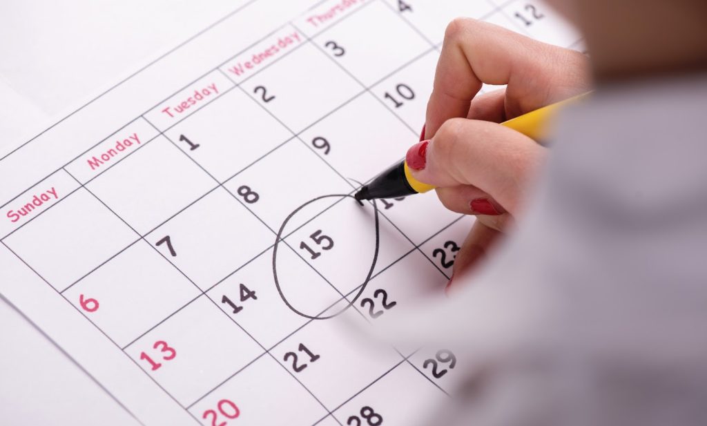 a woman circling a date on a calendar with a pen