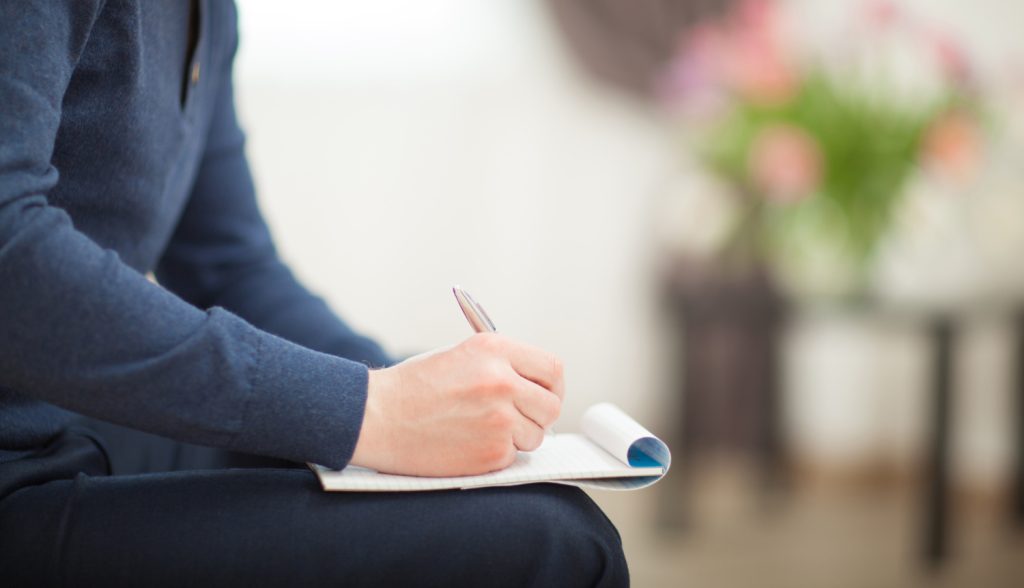 a woman sitting in a room making a list