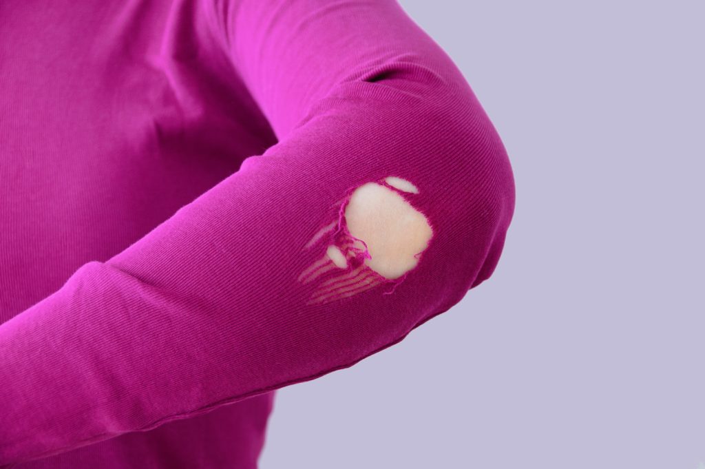 a women with a hole in the elbow of her pink shirt