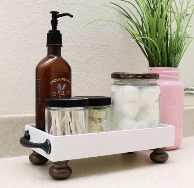 Image that shows a tray that hold glass jars with lids. Each jar organizes Q-tips, cotton balls and soap.
