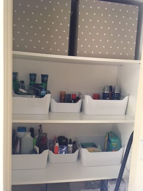 Image that shows a closet with boxes on a shelf to organize towels. 