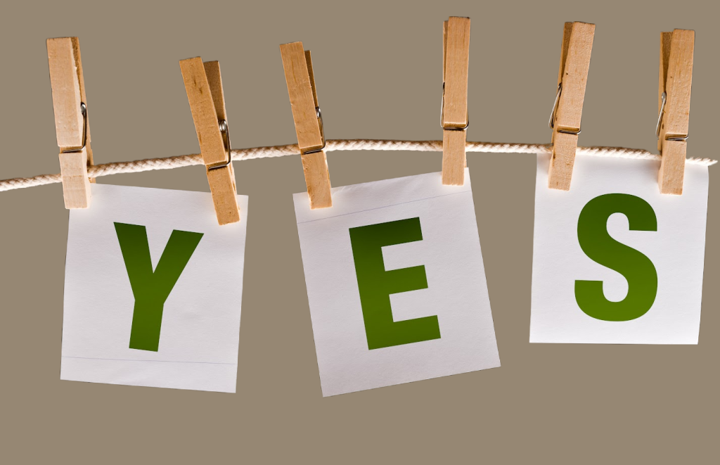 green Yes words hung up with clothes pins on a string