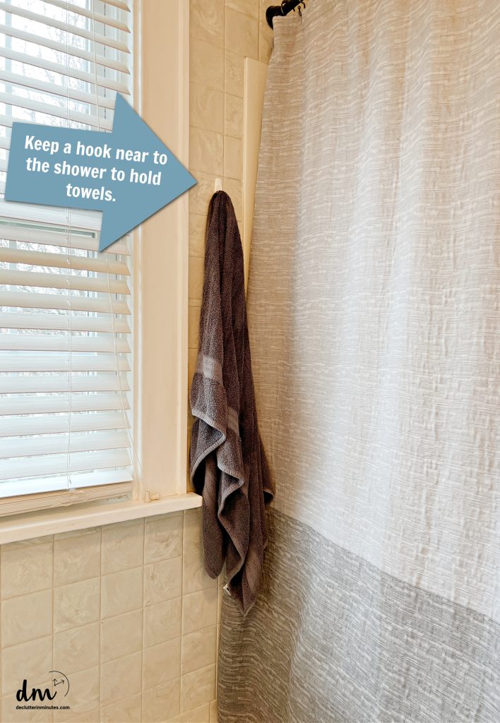 a grey towel hanging on a hook in a bathroom with a blue arrow pointing to it