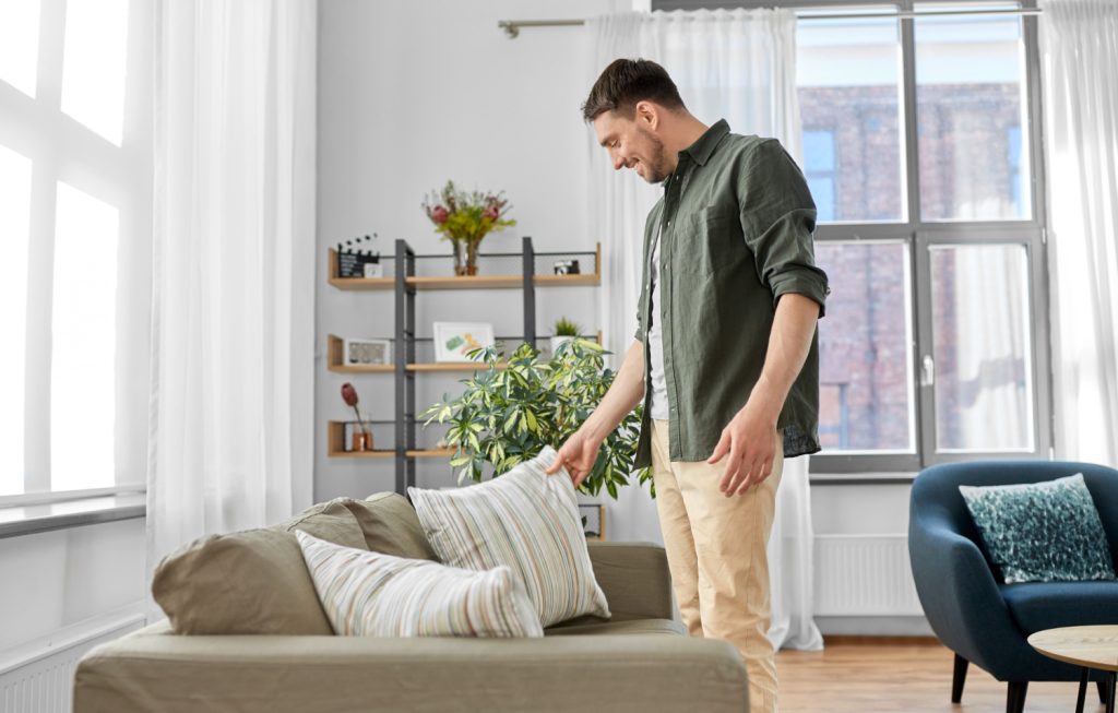 a man in a green shirt putting a pillow on a couch