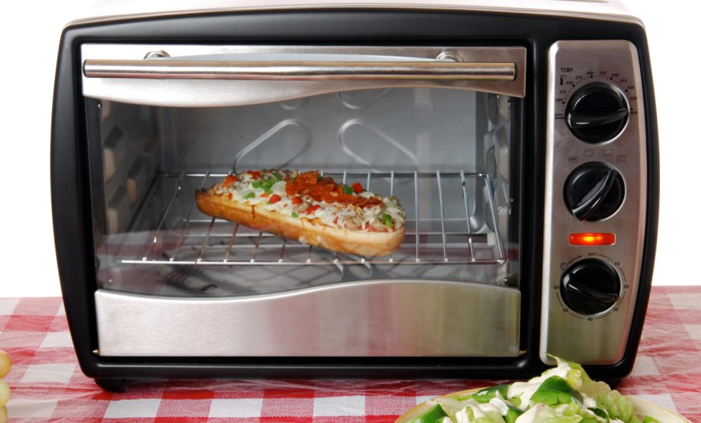 A frozen pizza heats in a toaster oven