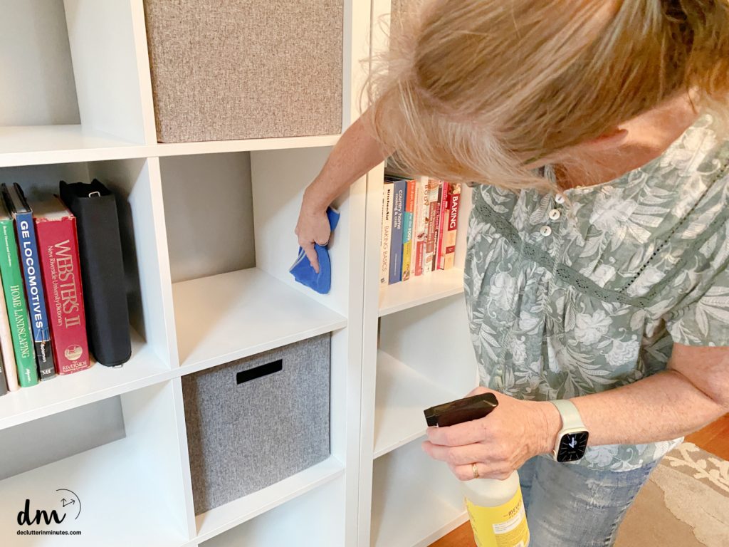 a woman cleaning a bookshelf in a family room
