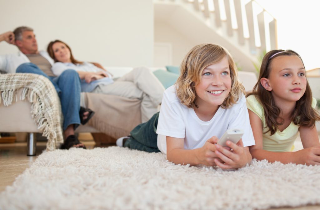 Siblings lying on the carpet watching tv together