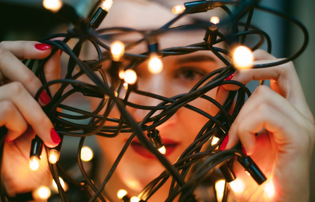 a woman looking through a tangle of lights she is holding in her hands