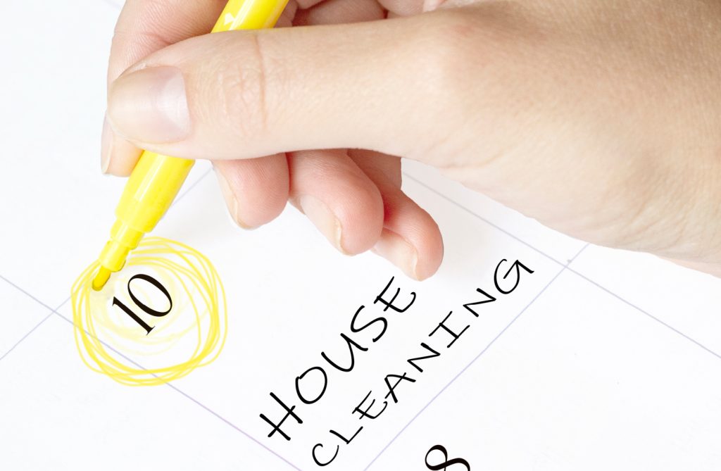 a hand highlighting a calendar with the words house cleaning written on it.