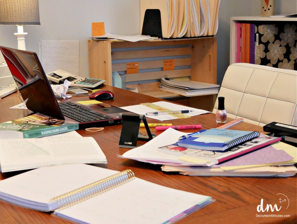 a messy desk covered in papers books and clutter