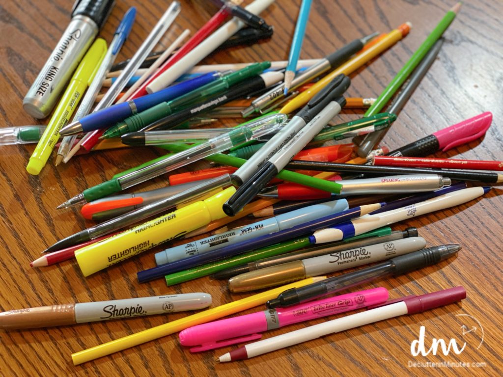 a pile of pens, pencils, and markers in a pile on a desk