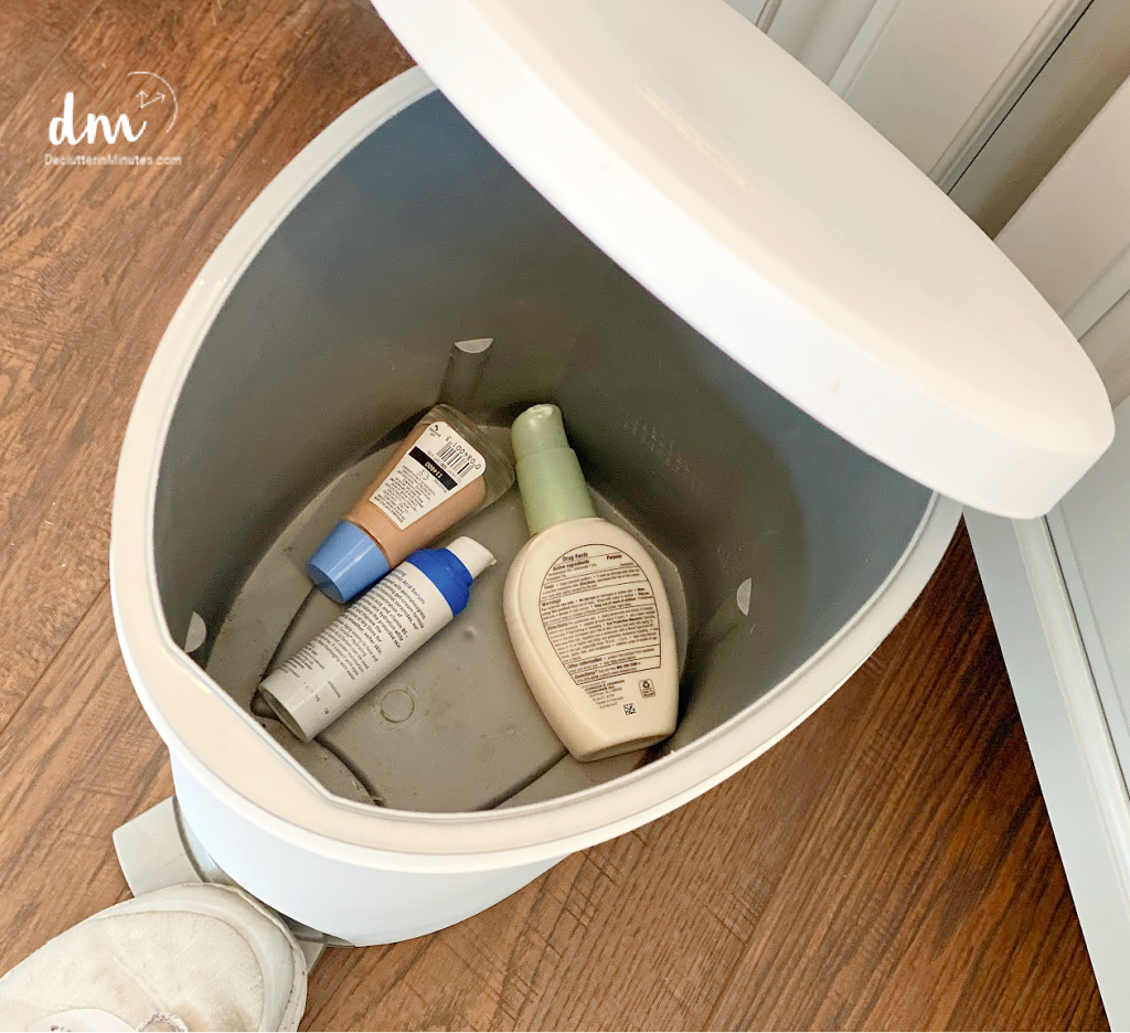 a white trash can with old makeup and lotions inside