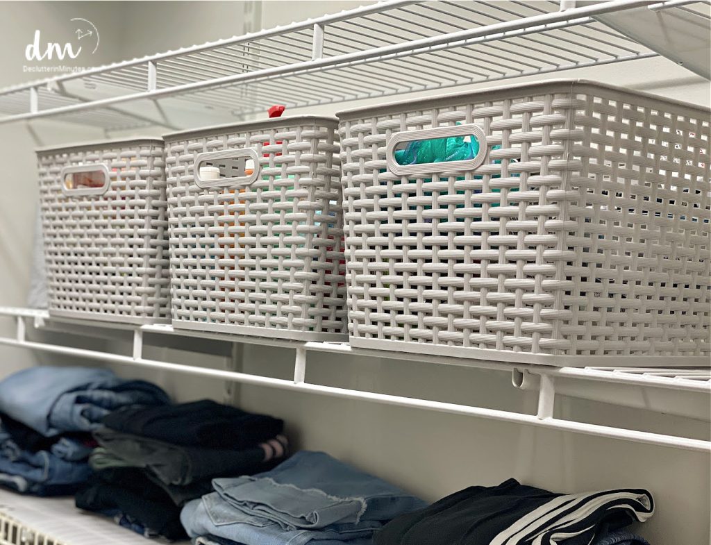 three grey plastic baskets on a closet shelf