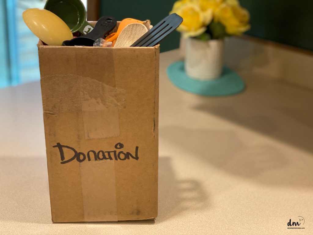 a box labeled donation on a kitchen counter full of stuff