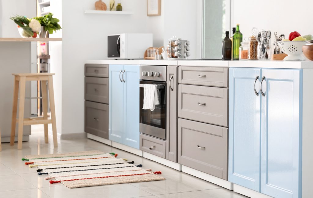 A striped rug on the floor of a white kitchen.