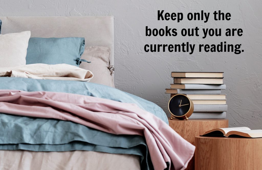 a stack of books next to a bed.