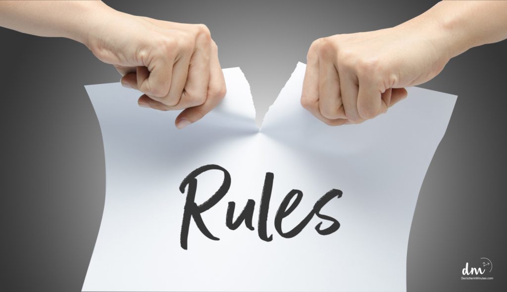 Woman hand ripping white paper with RULES written on it on gray background