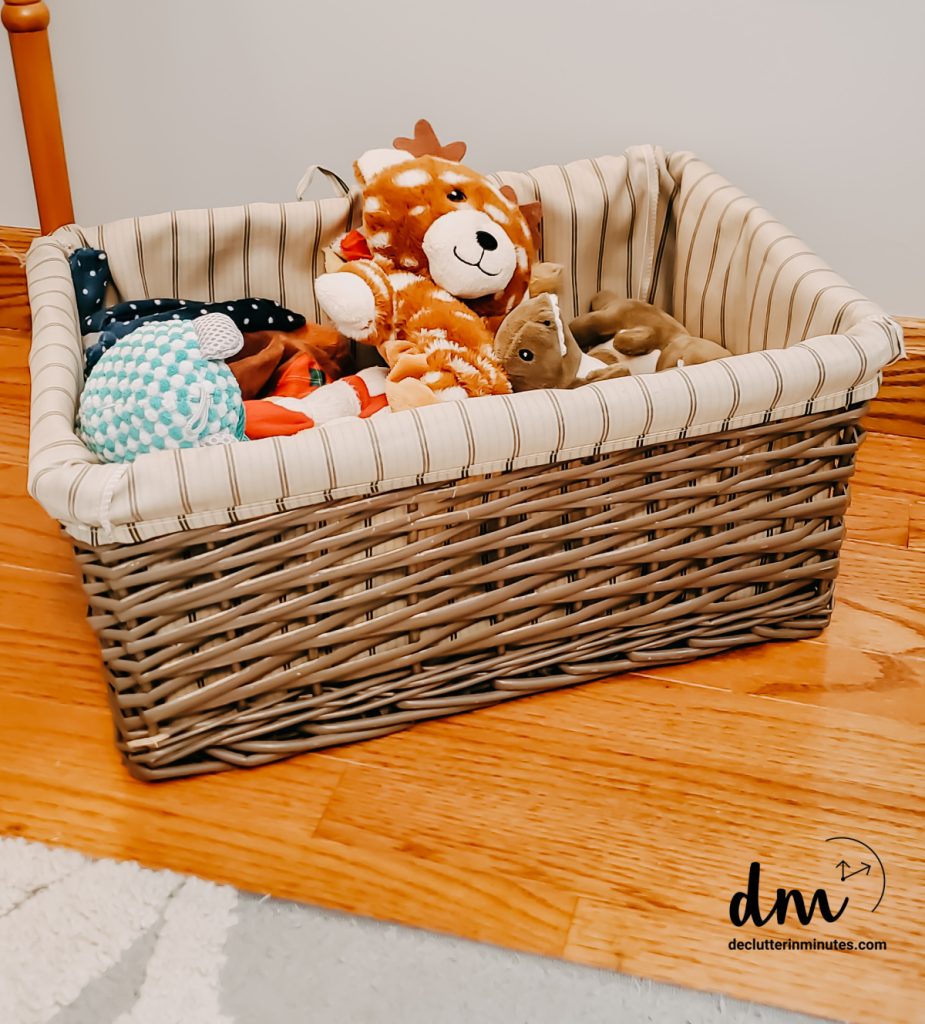 A basket of dog toys on a hardwood floor