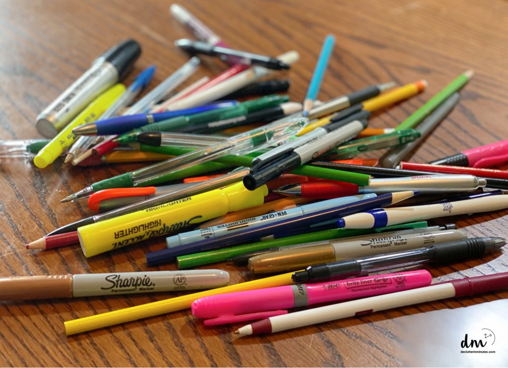 A pile of pens, pencils, and markers on a desk