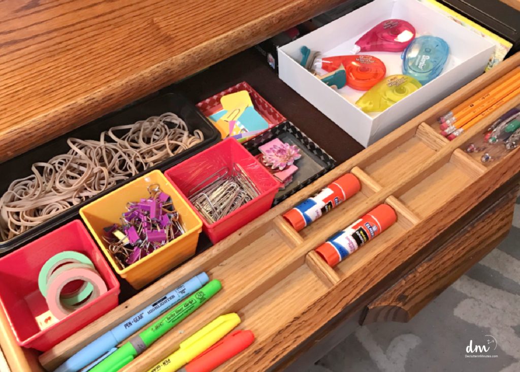 a drawer in a desk with office supplies in small containers