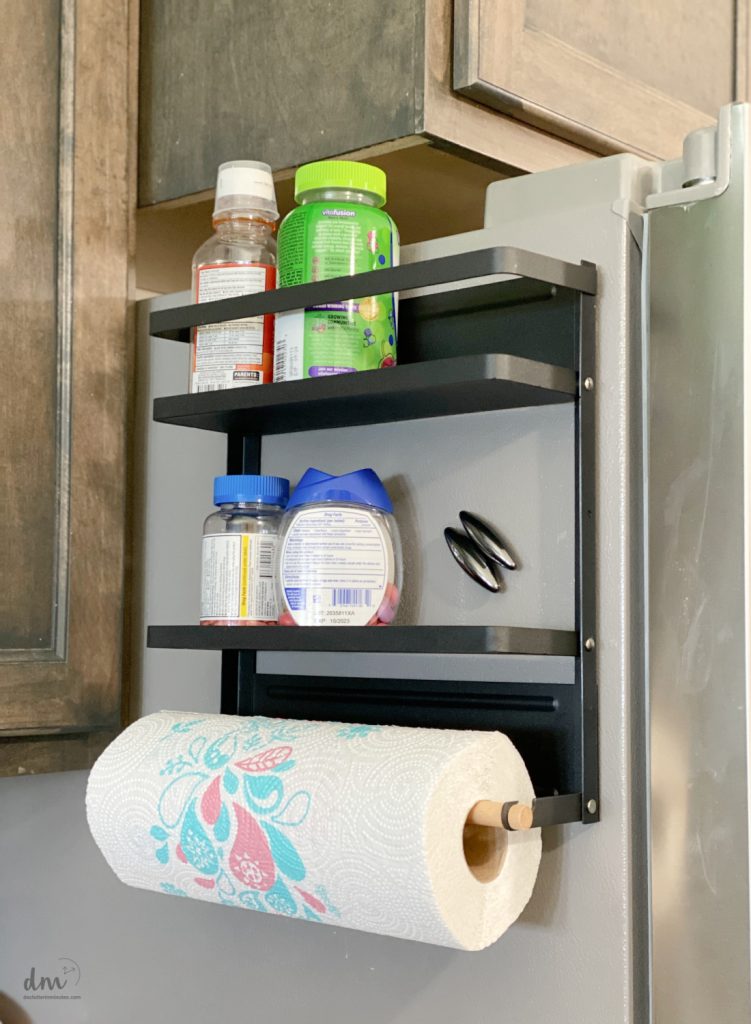 a magnetic organizer on the fridge in a kitchen holding pills and paper towels