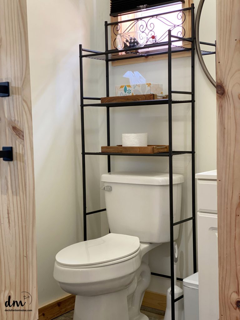 a shelving unit over a toilet seat in a bathroom