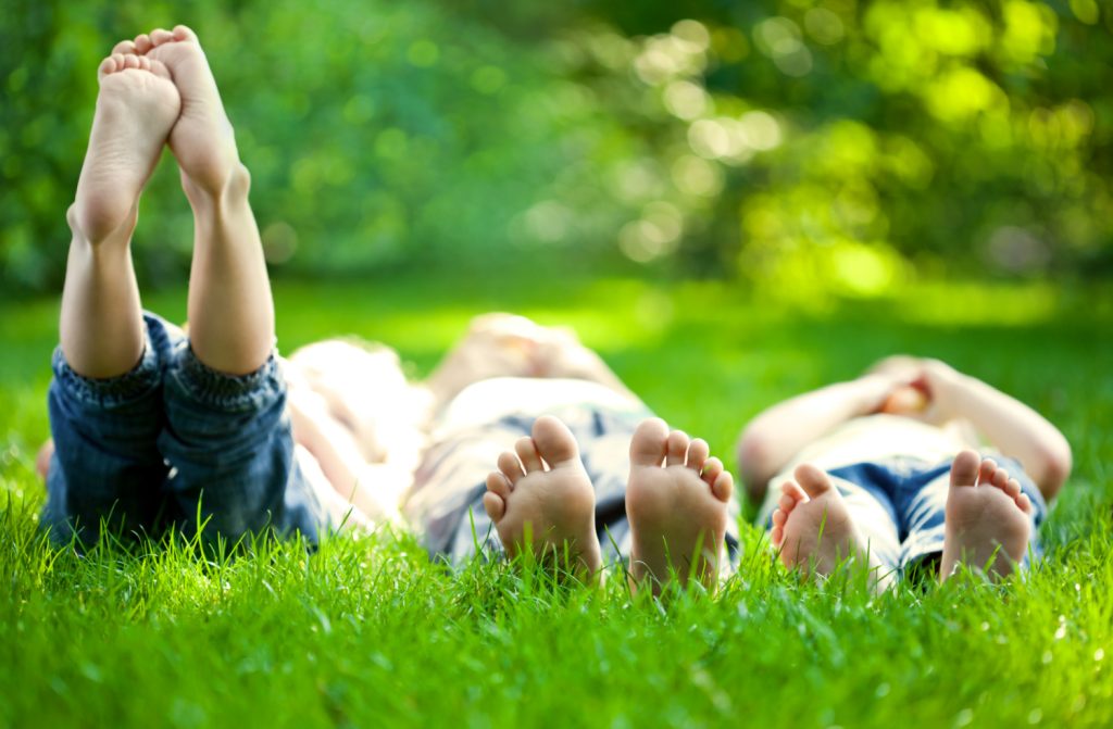 Group of happy children lying on green grass outdoors in spring park