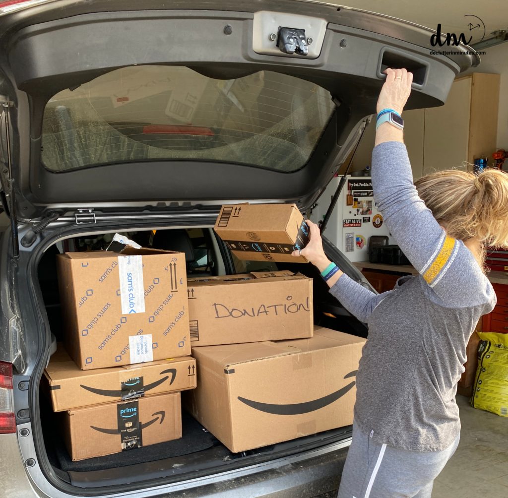 a woman putting boxes of donations in a car trunk