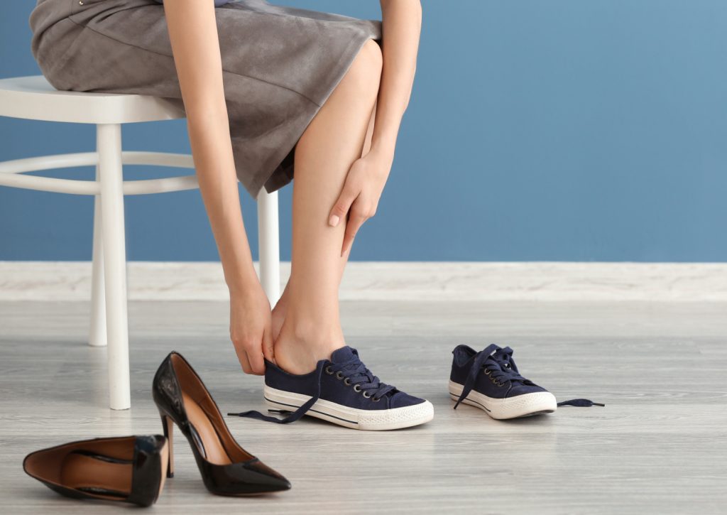 Tired young woman sitting on a chair changing shoes in her organized closet
