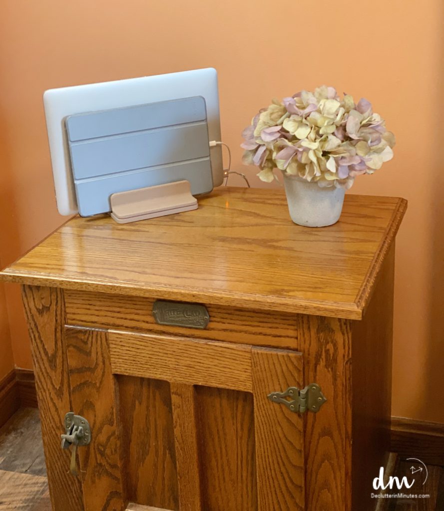 A standing holding a laptop and ipad near to flowers