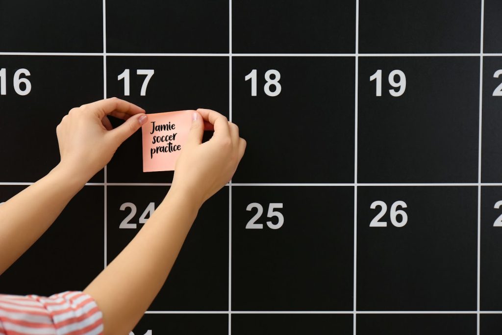 hands putting a pick sticky note on a black calendar 