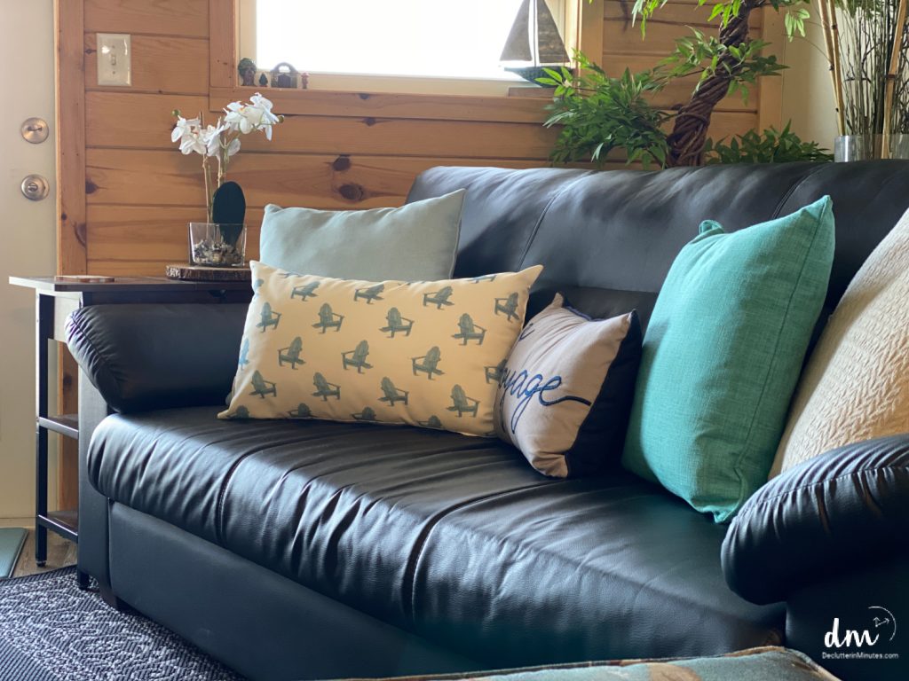 a dark couch filled with light colored pillows in a family room
