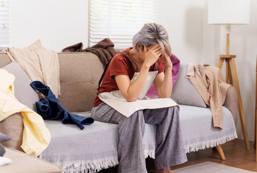 a woman frustrated on a couch surround by clutter