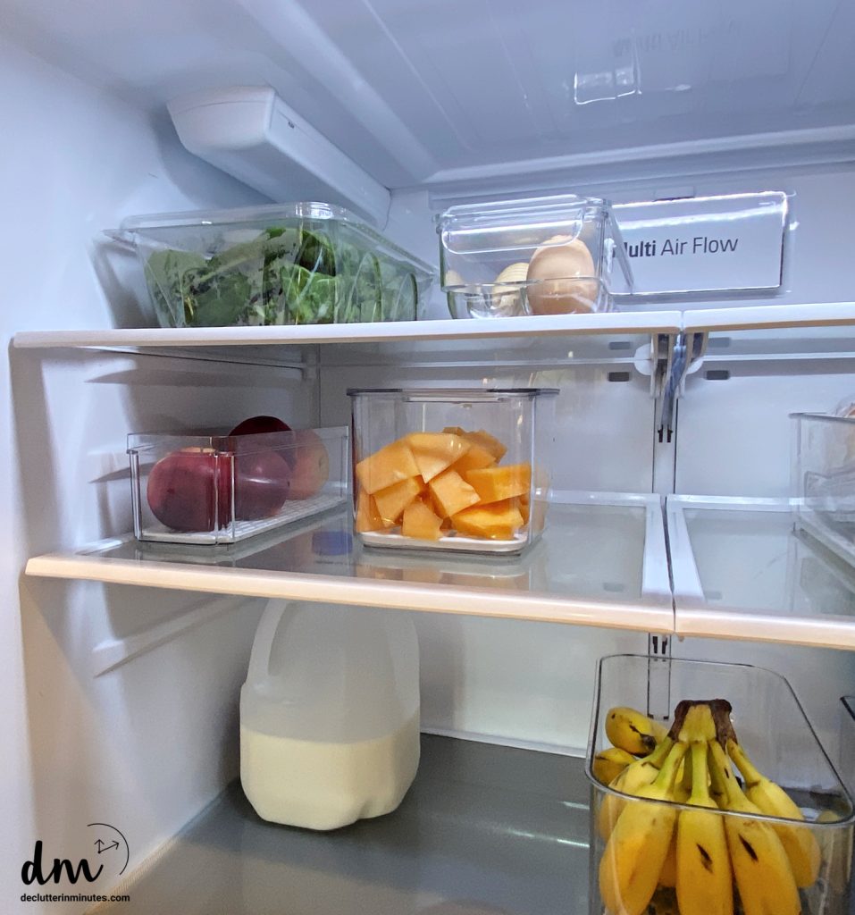 an organized refrigerator with produce containers filled with fresh cut fruit and vegetables