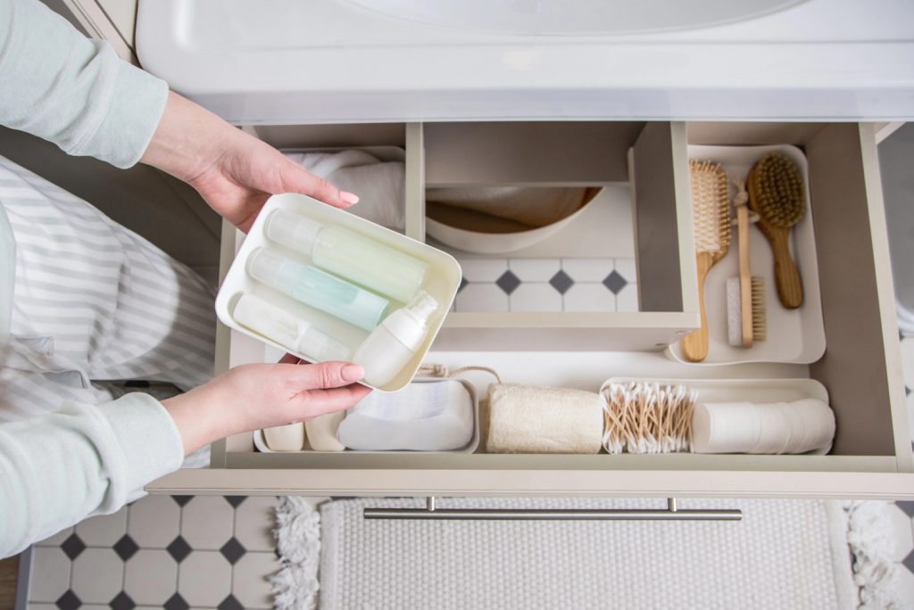 hands putting organizers into a newly decluttered bathroom