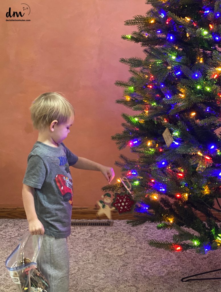 a little boy putting an ornament on a Christmas Tree