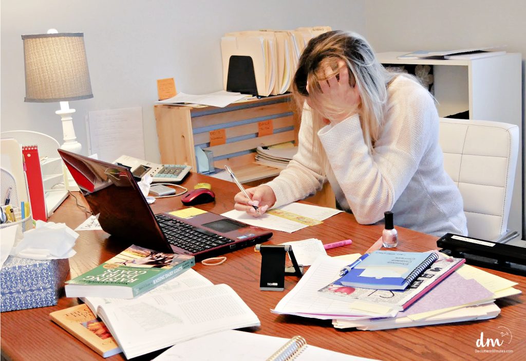 a woman head in hand trying to work with a messy desk