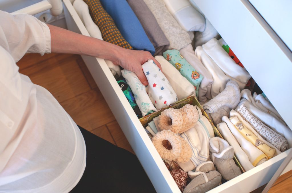 a woman putting clothes away in a dresser drawer