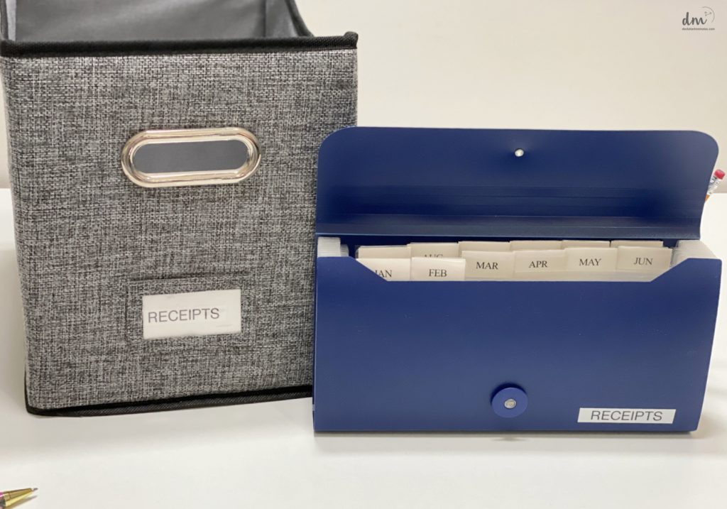 a blue file folder for receipts next to a grey canvas bin