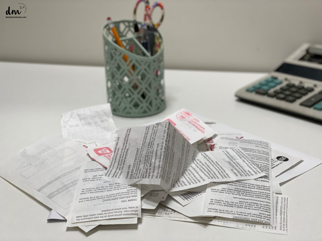 a stack of paper receipts on a table near to a container of pens