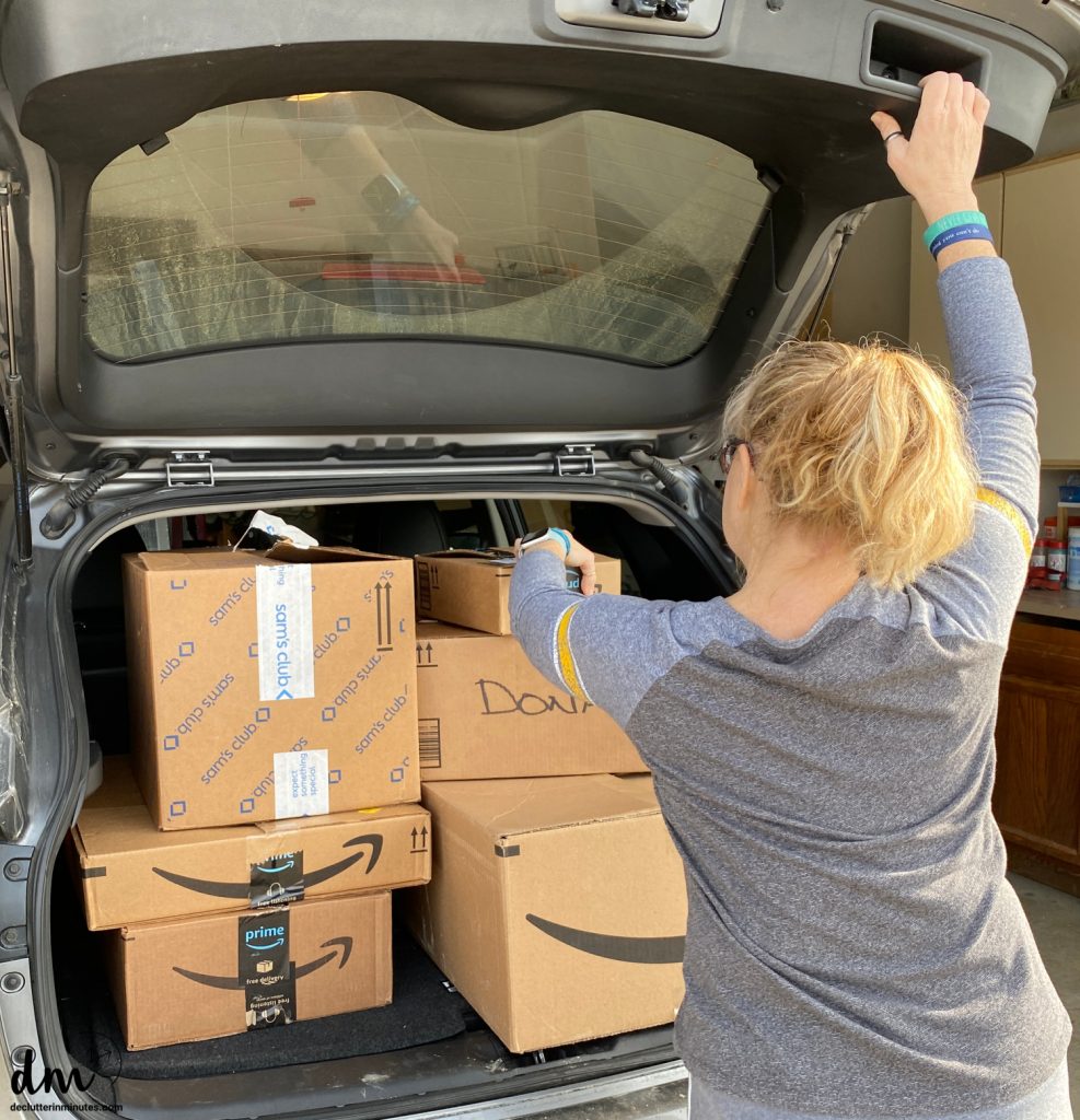 a woman putting donation boxes into the back of her car