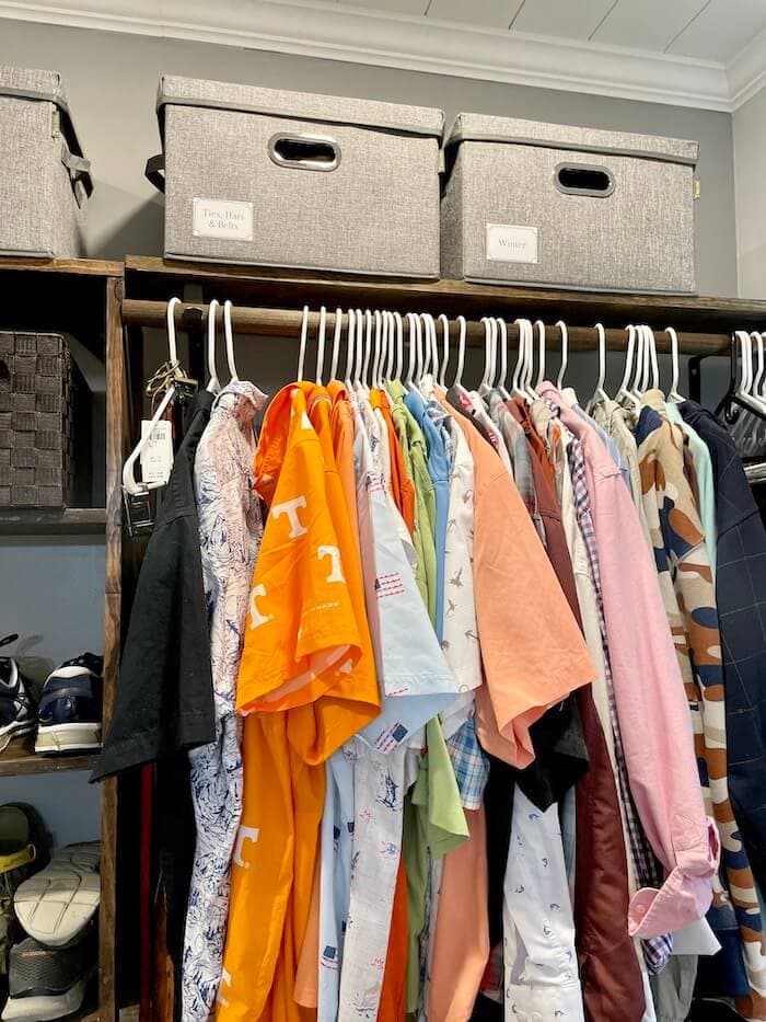 storage boxes in the top shelf and clothes on hangers