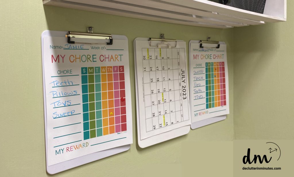 White clipboards with chore charts and a calendar on them.