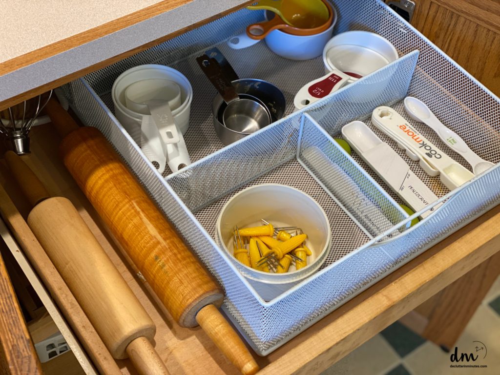 a white organizing basket with measuring tools inside and rolling pins outside