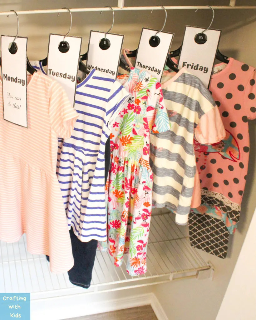 children's clothing in a closet with hangers labeled with tags for each day of the week