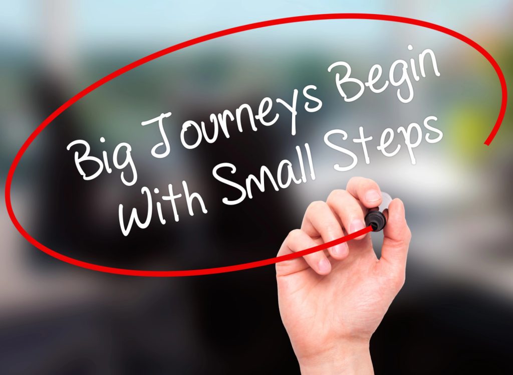 hand circling the words big journeys begin with small steps 