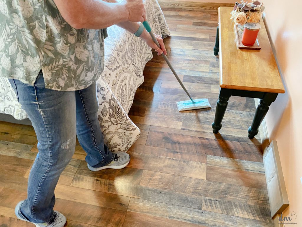 a woman using a floor swiffer to clean the floor in a bedroom