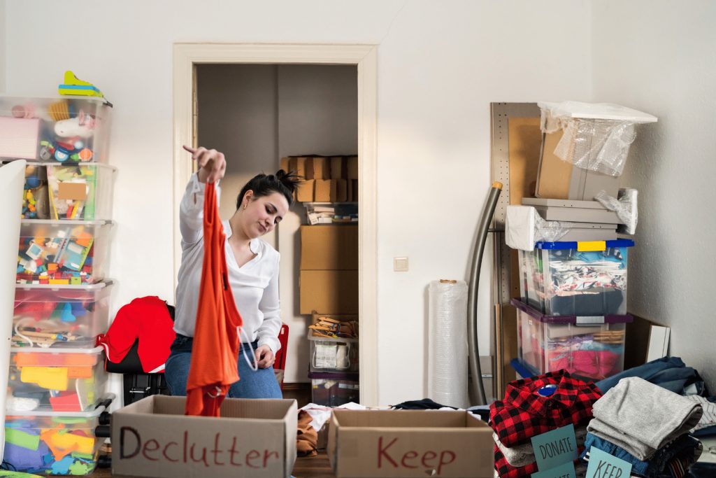 woman sorting old household items like clothes and toys before a garage sale